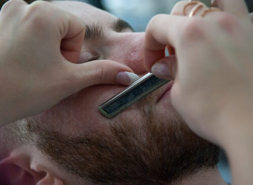 カミソリでヒゲを剃られる男性